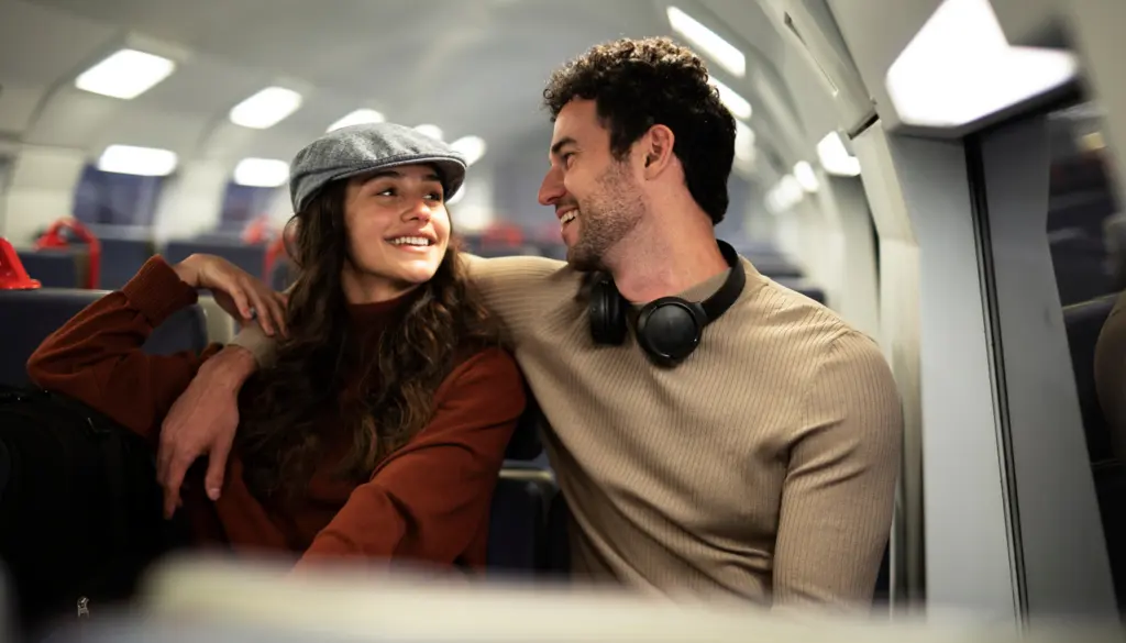 Two travellers smiling on a train.