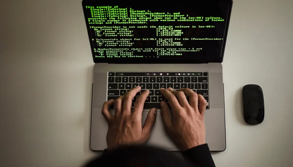 Hands typing code on a laptop.
