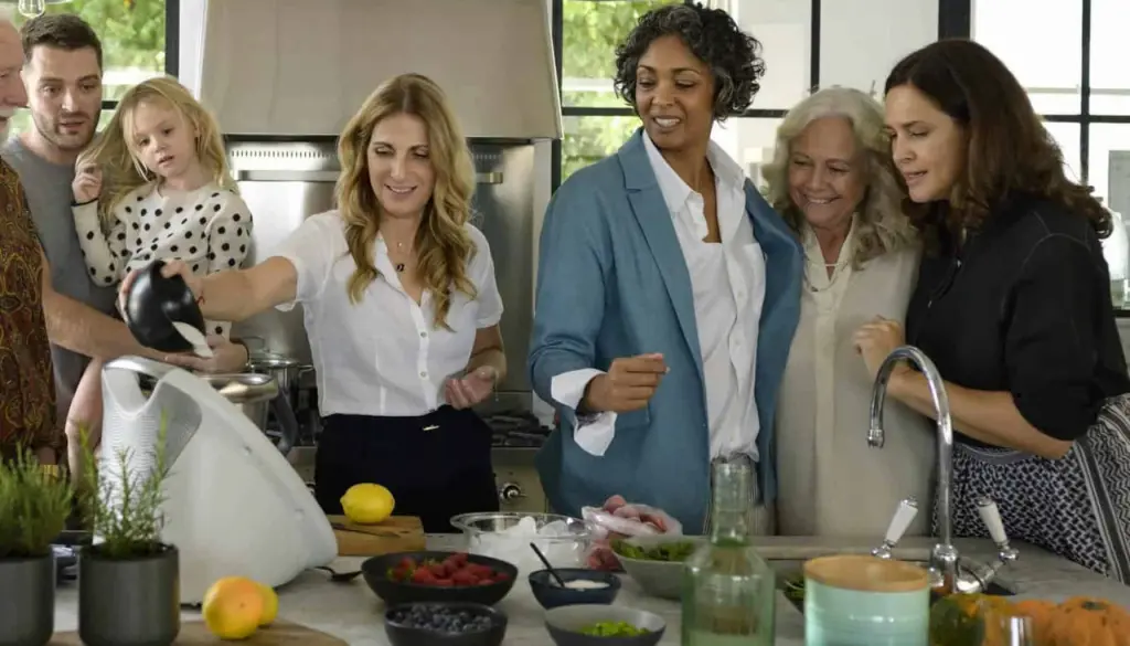 Friends cooking together around a Thermomix in a home kitchen.