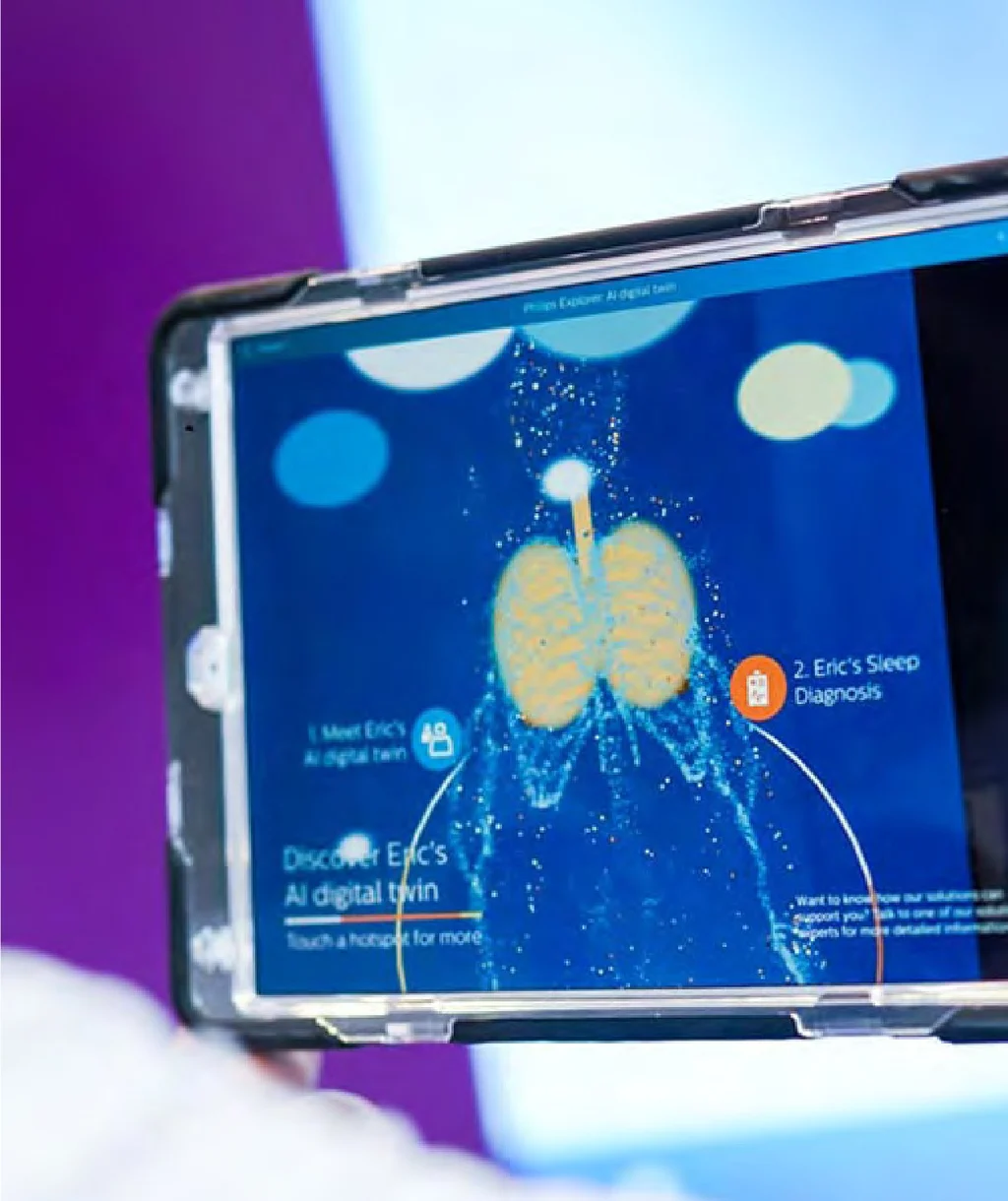 A tablet showing Eric's AI digital twin: a pair of lungs in points of light, with hotspots to meet Eric's digital twin and to see his sleep diagnosis.